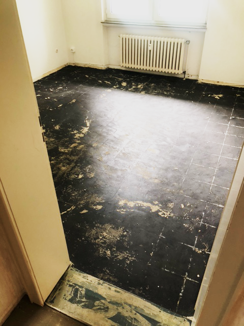 chwarzer PVC-Bodenbelag mit Kleberesten – potenziell asbesthaltige Floor-Flex-Platten in Wohnraum